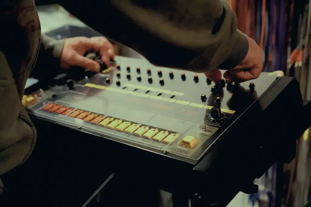 Hands adjusting a Roland TR-808 drum machine