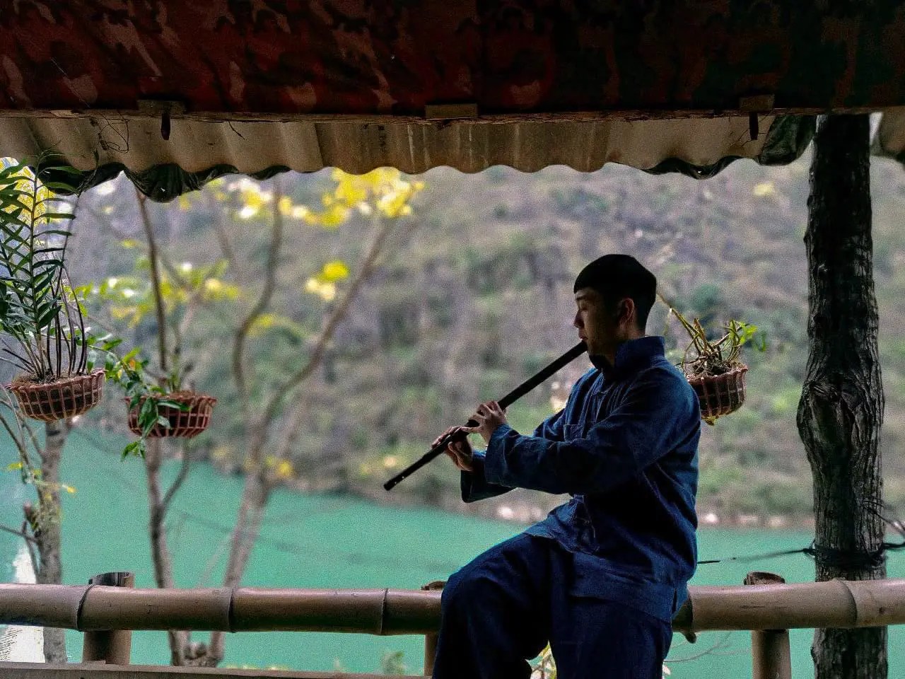 A musician playing a wind instrument beside a lake in Northern Vietnam during the Ha Noi recording sessions.